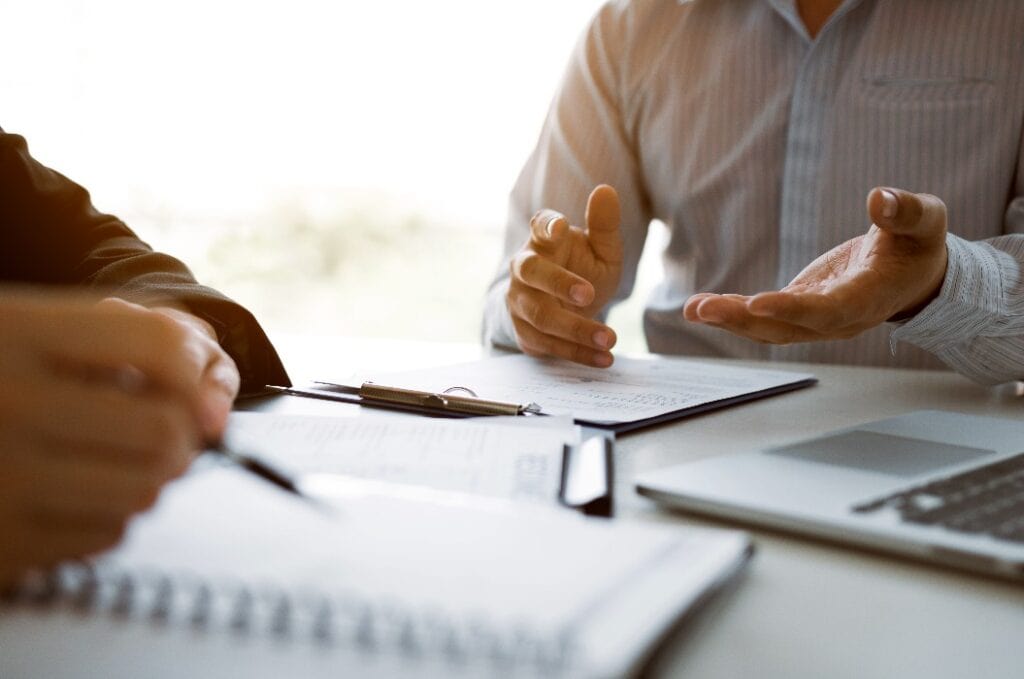 Male employee is explaining to the manager while being interviewed in the office room.